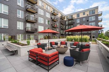 a patio area with red couches and umbrellas surrounding a fire pit in the zen garden